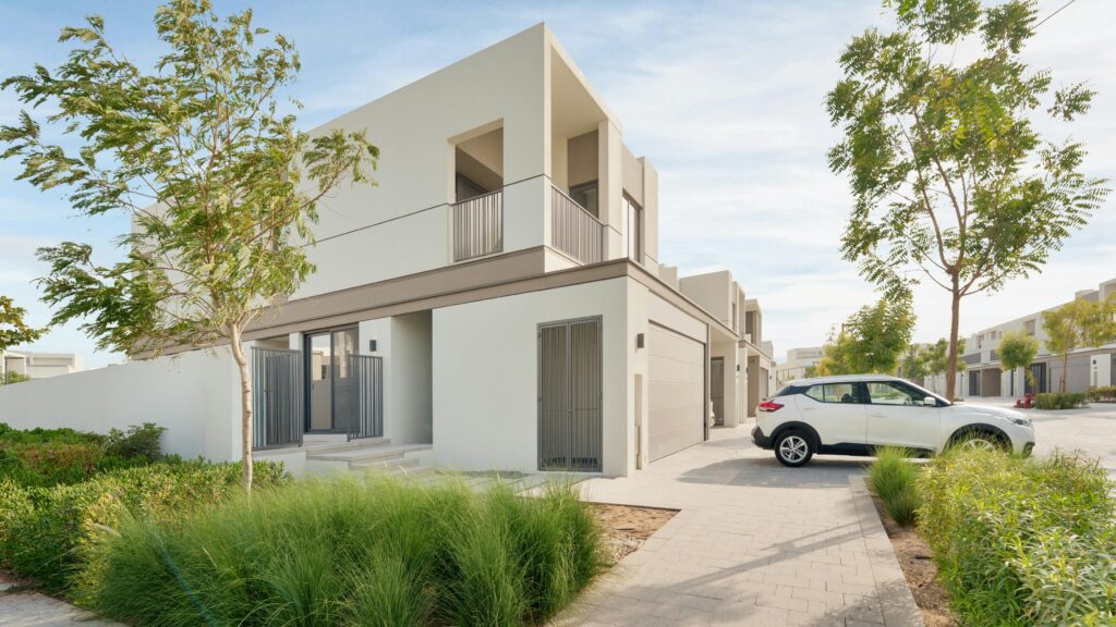 Contemporary villa in Dubai with a parked car, surrounded by lush greenery.
